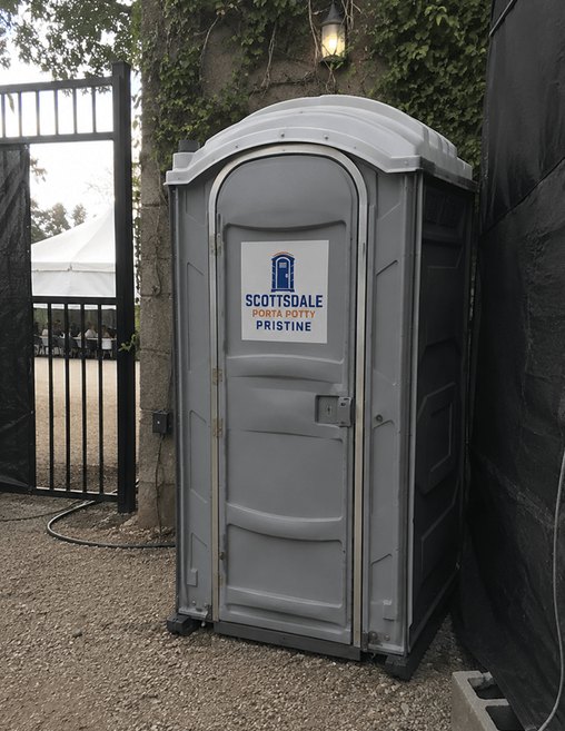 Event porta potty rental placed beside a service gate at a private party